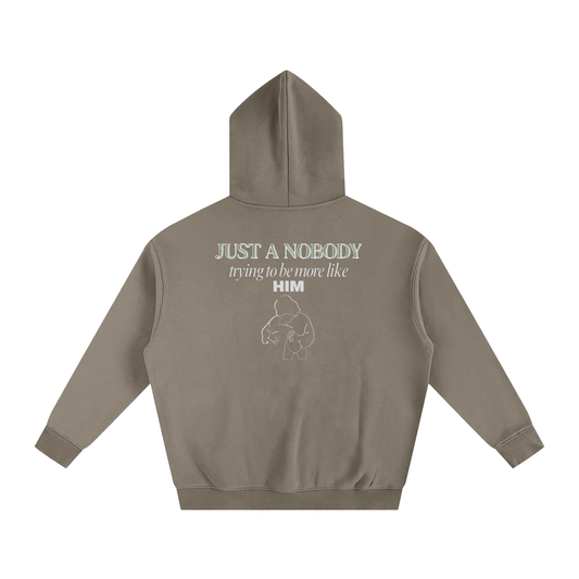 Brown/Khaki hoodie with text and graphic on the back against a white background. Text says 'Just a nobody trying to be more like him' with an outline graphic of Jesus embracing a child.