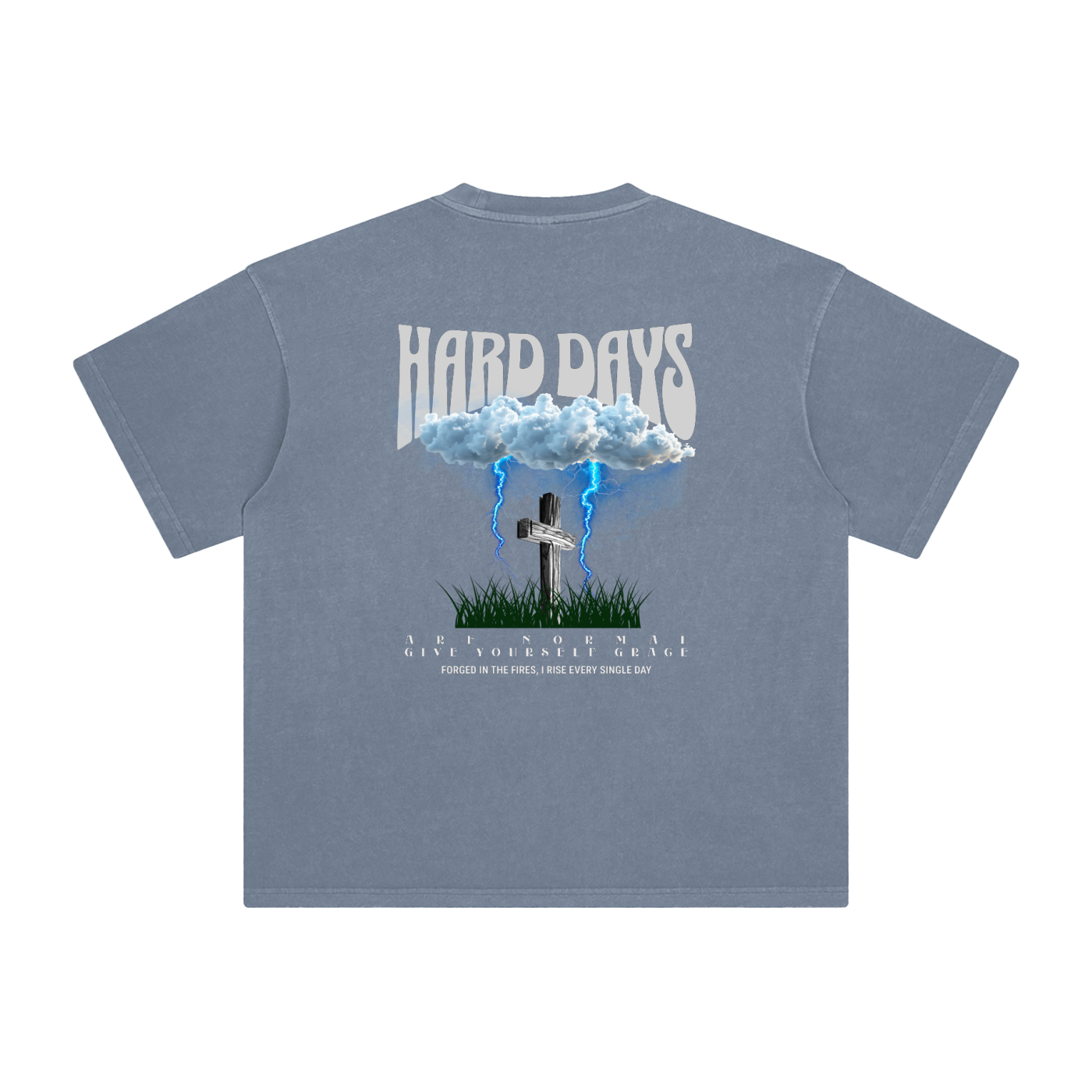 Gray Blue t-shirt with graphic design and text on the back. Graphic design consists of Clouds with lightning, a cross, and some grass graphic. Bold text on the top says "Hard days" and bottom text saying "are normal" "Give yourself grace" "forged in the fires, I rise every single day". 