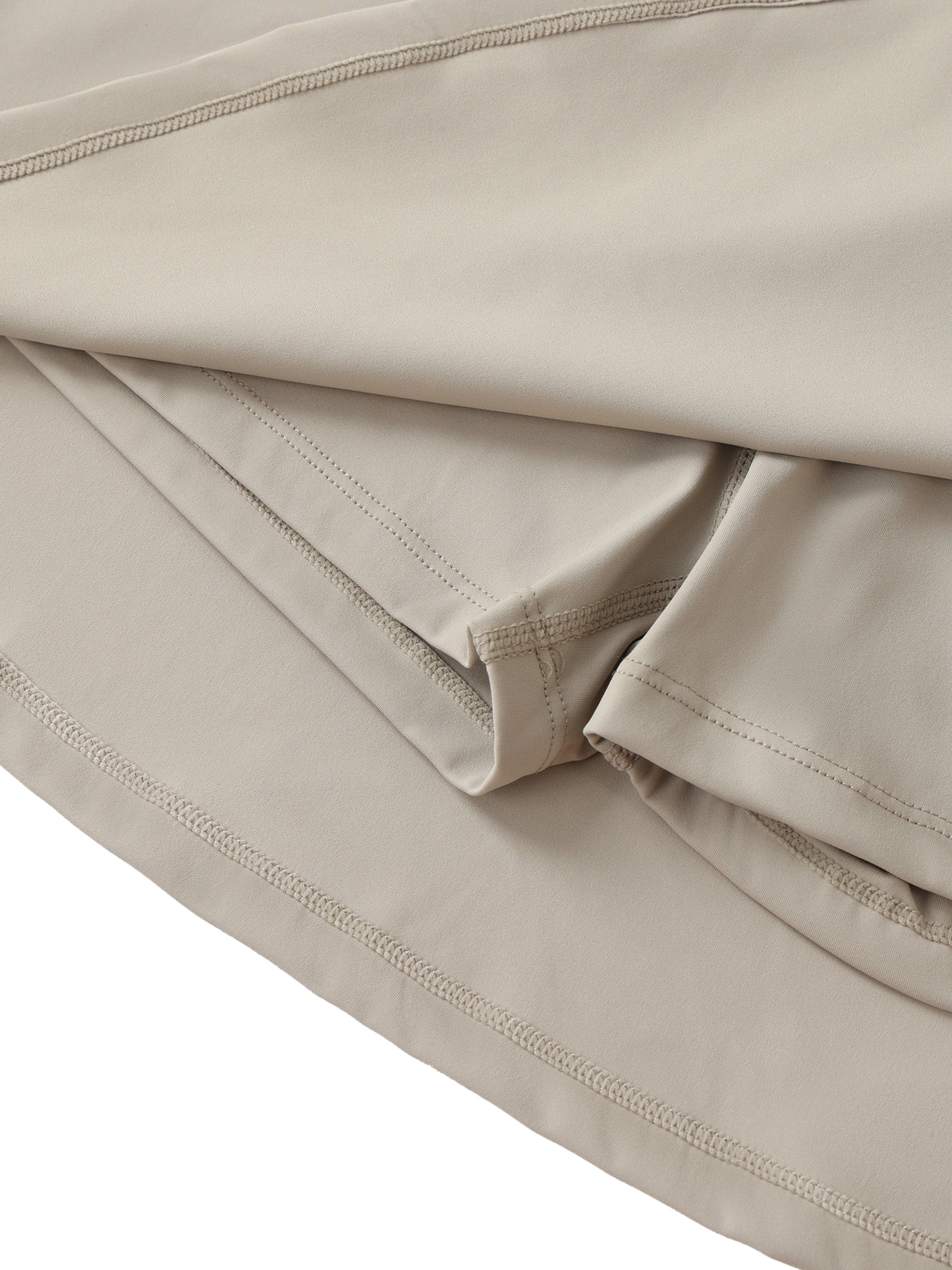 Close-up of beige fabric with visible stitching of sewn in shorts on a white background