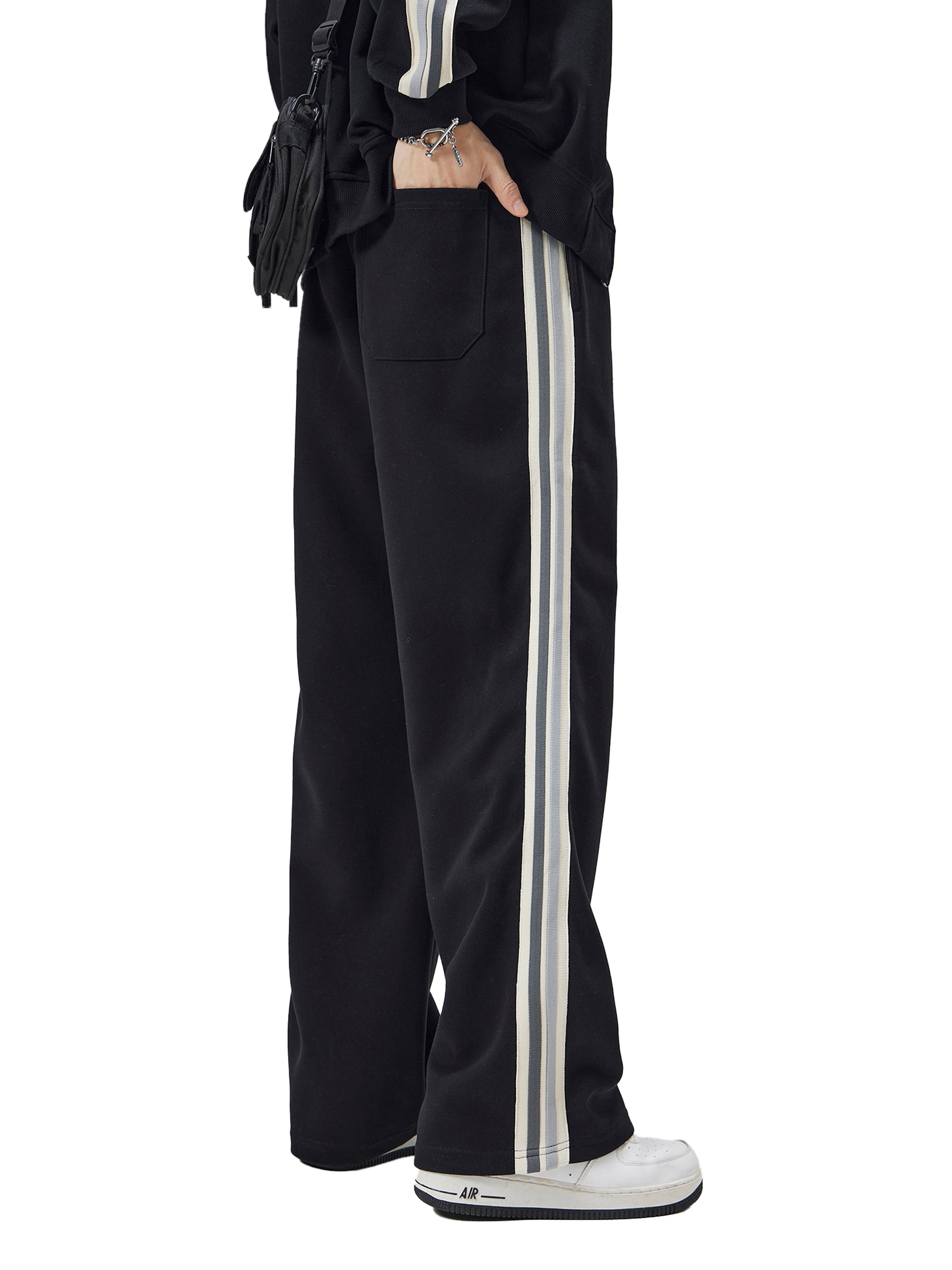 Black track pants with white stripes on a white background