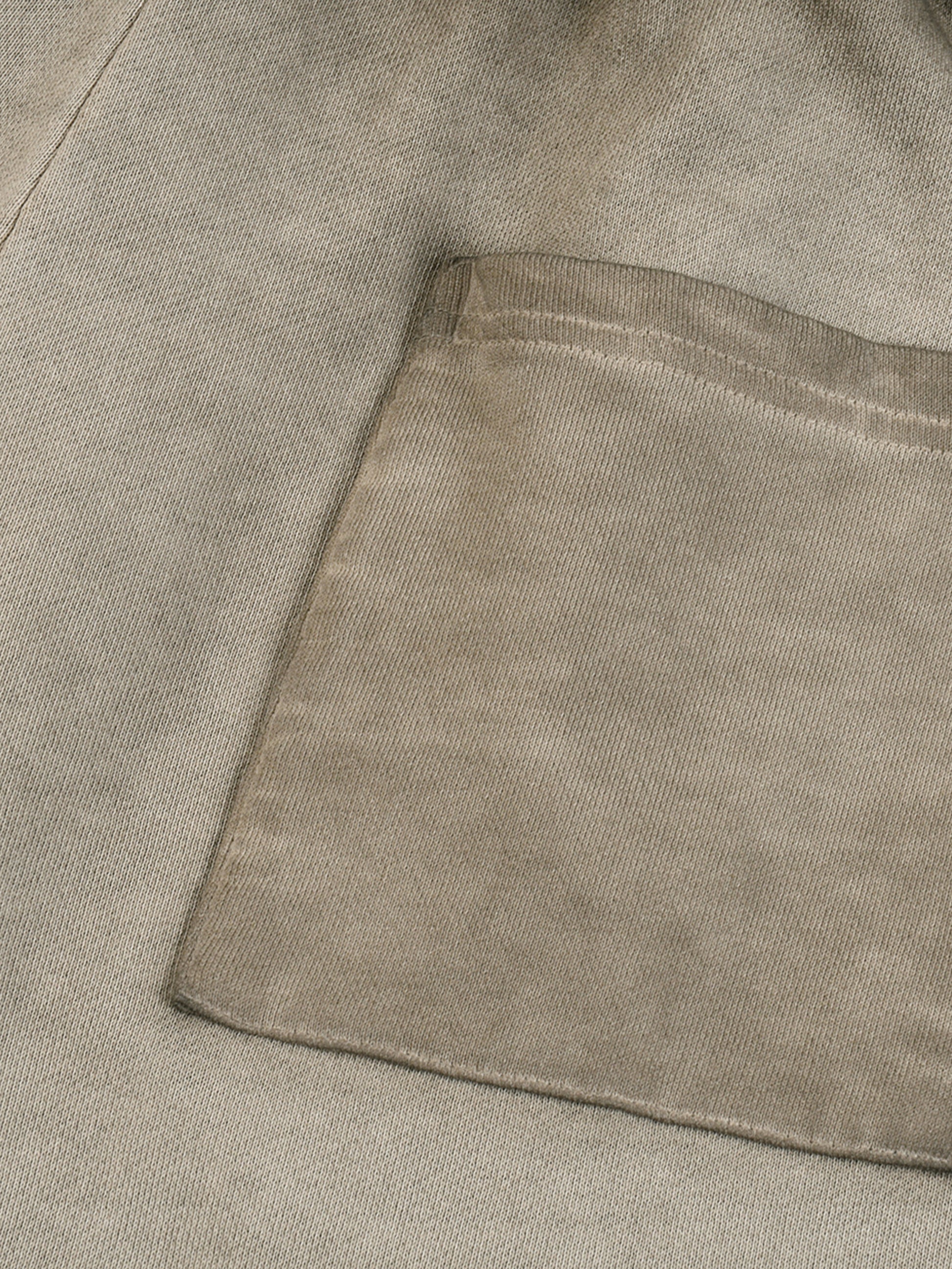 Close-up of a textured beige fabric with a pocket detail
