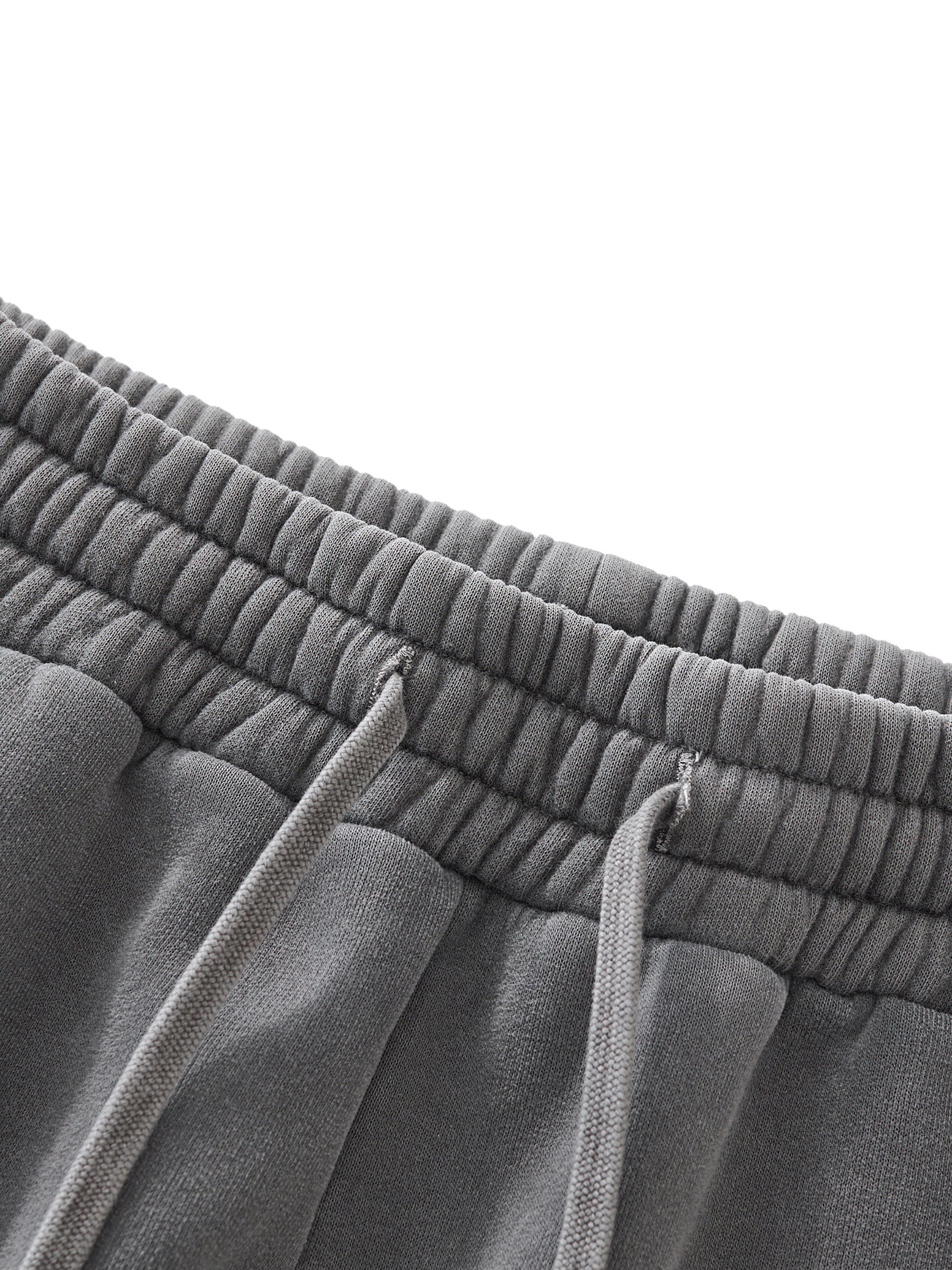 Close-up of gray sweatpants with drawstrings on a white background
