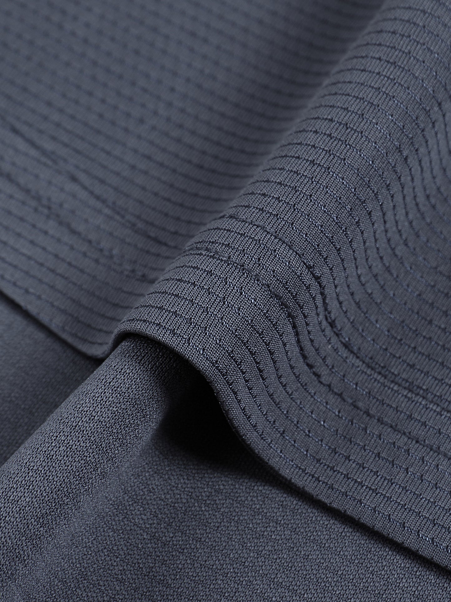 Close-up of textured dark gray fabric with a focus on the weave pattern.