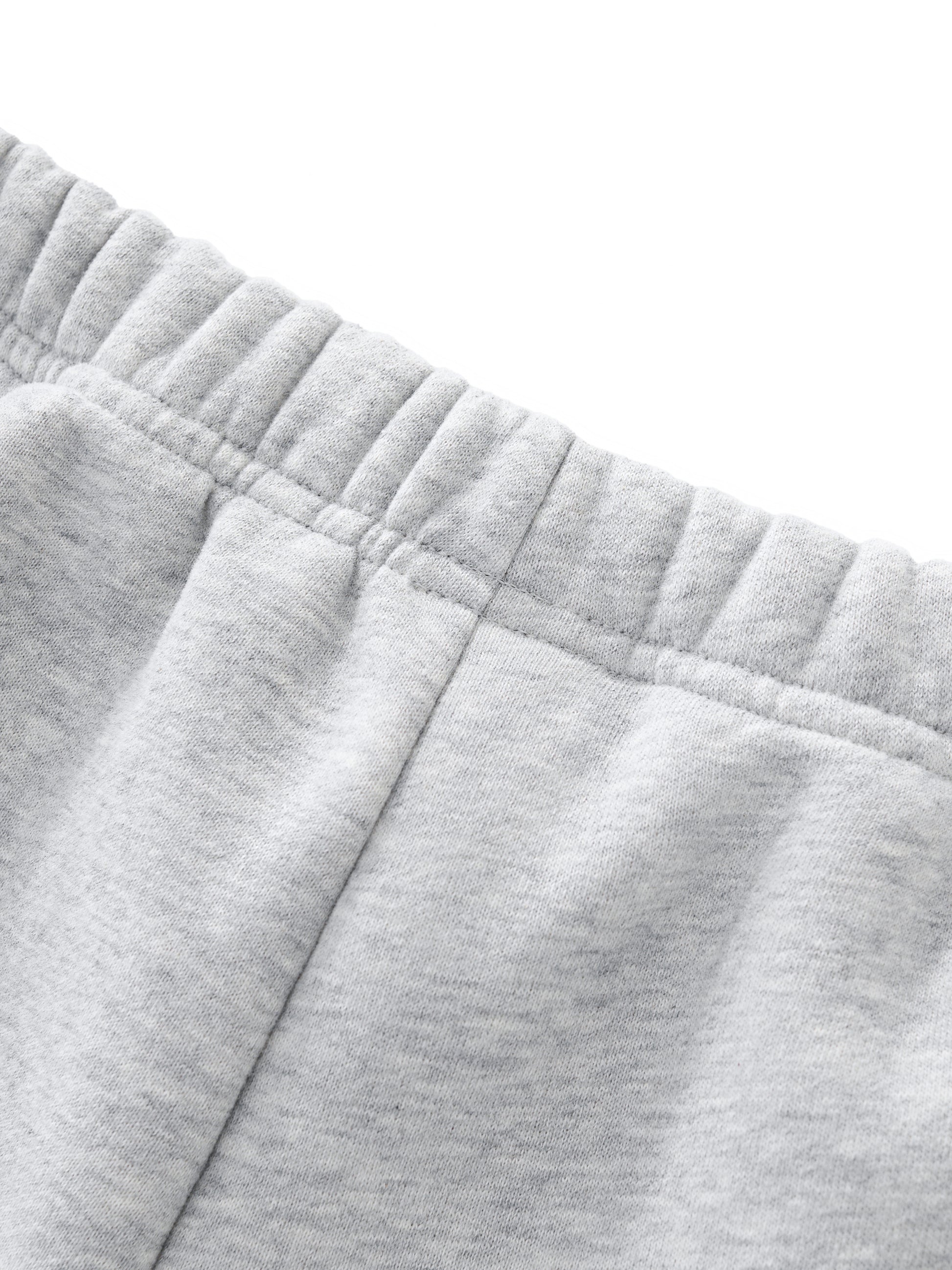 Close-up of gray sweatshorts in front of a white background, with an emphasis on the waistband