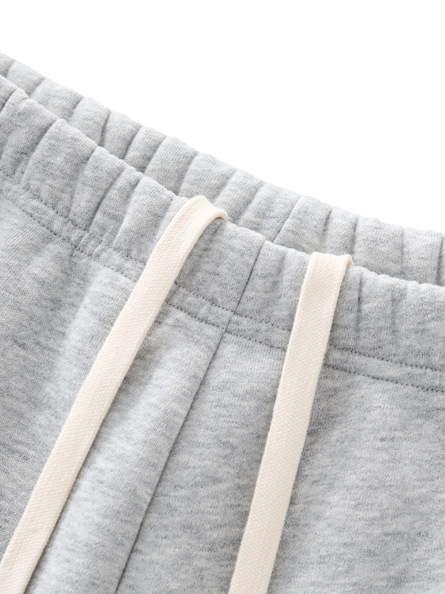 Close-up of gray sweatpants with beige drawstrings on a white background