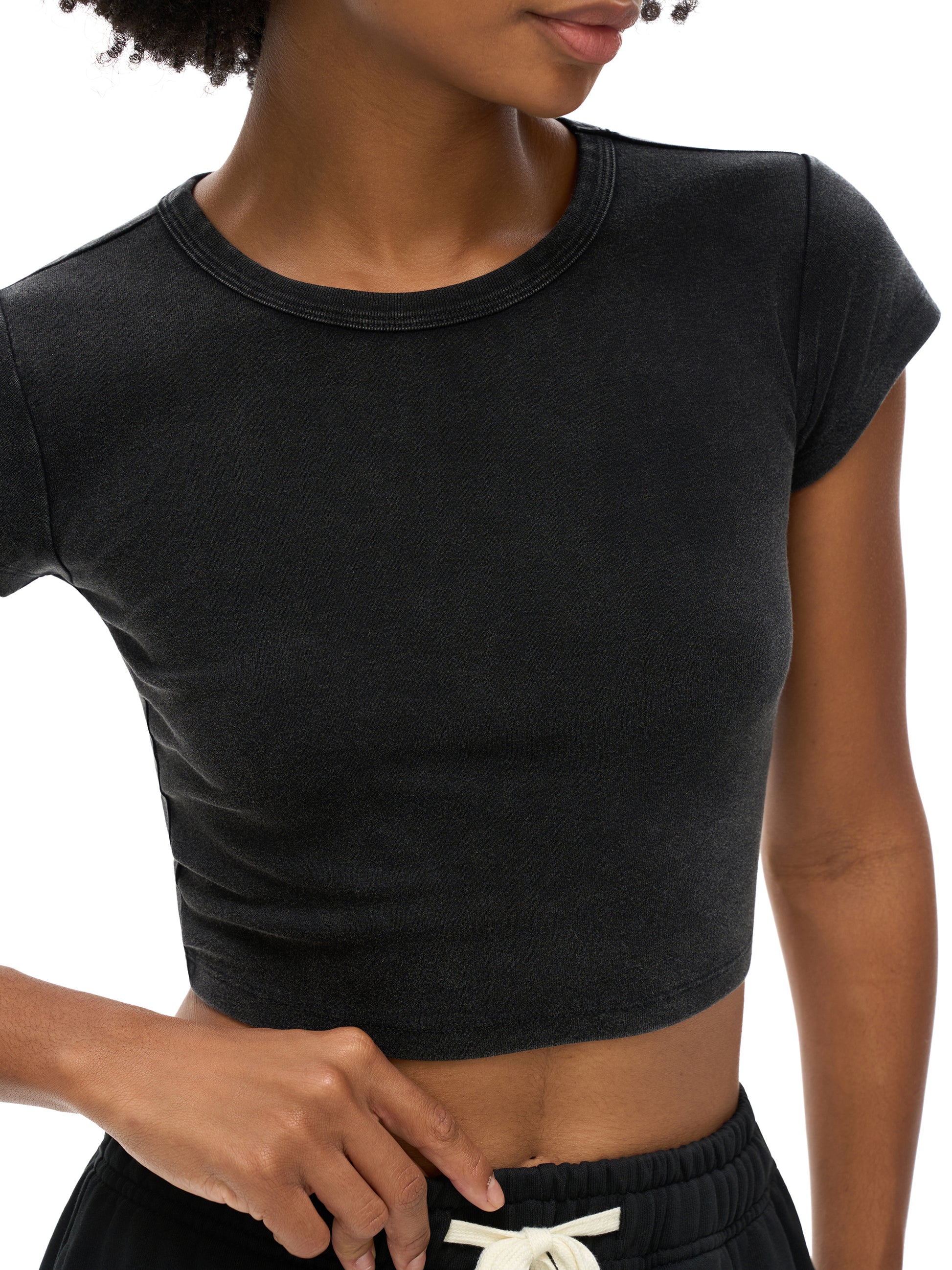 Person wearing a black crop top against a white background