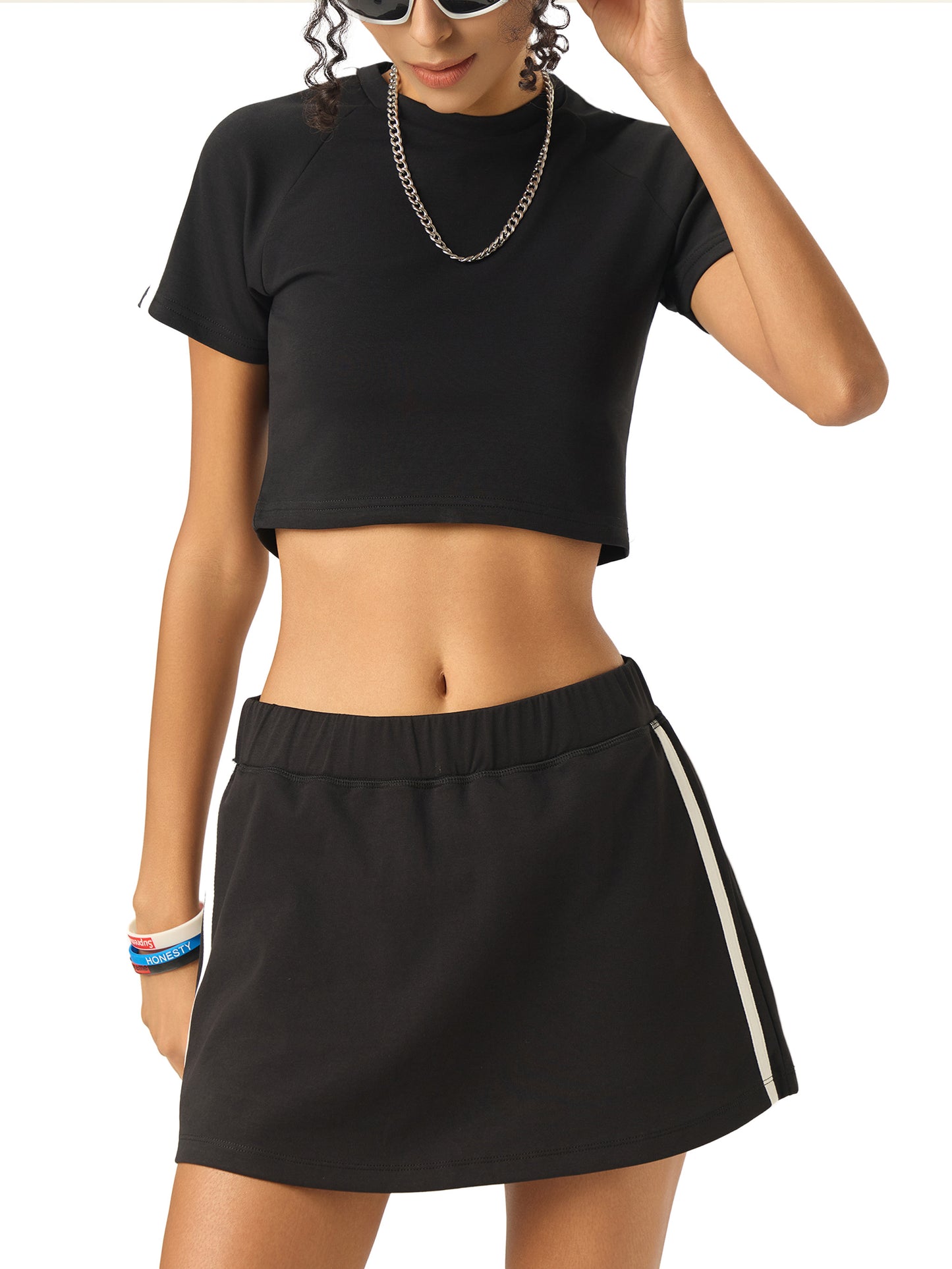 Person wearing a black crop top and black skirt with a white stripe on a white background