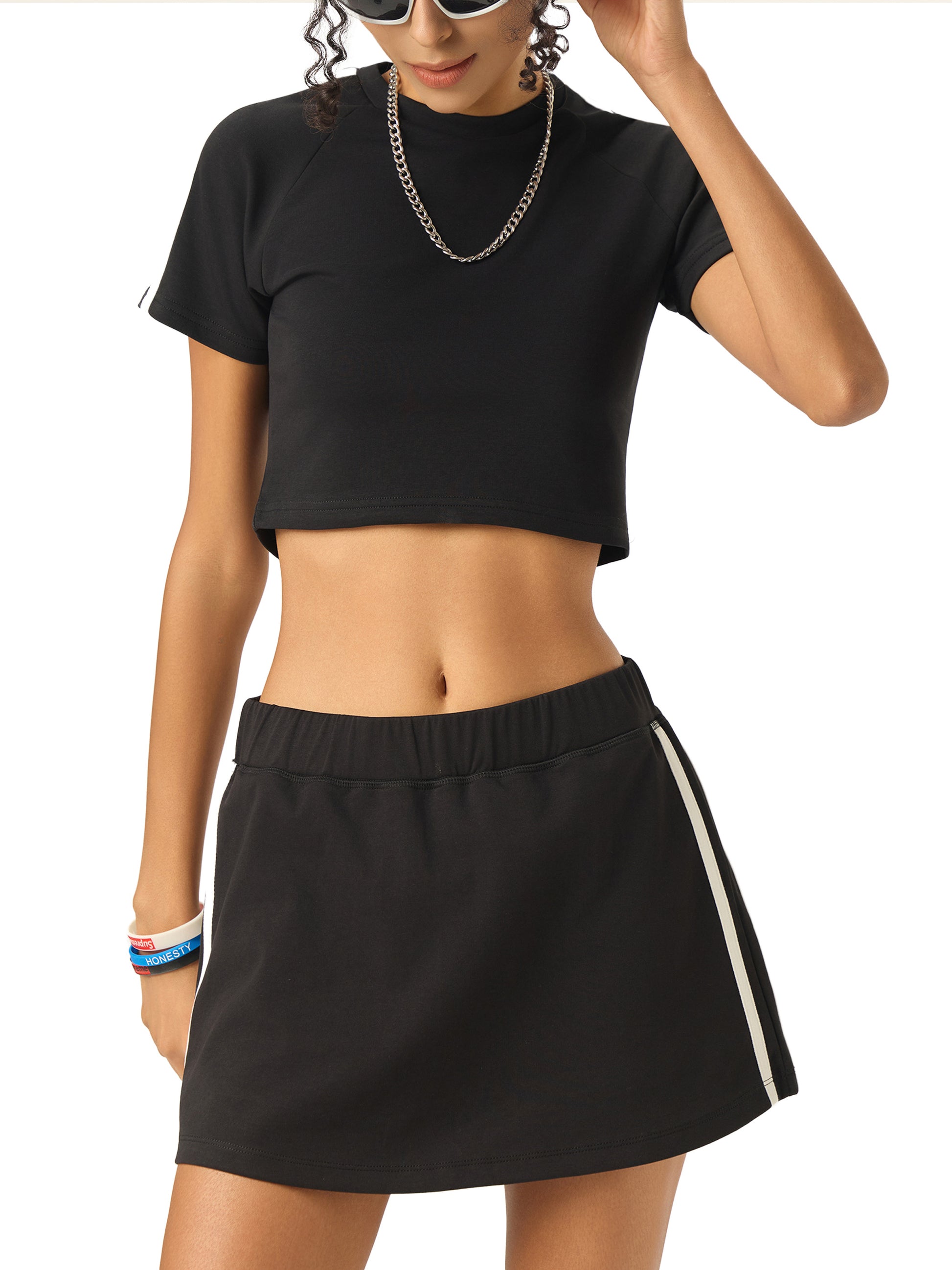 Person wearing a black crop top and black skirt with a white stripe on a white background