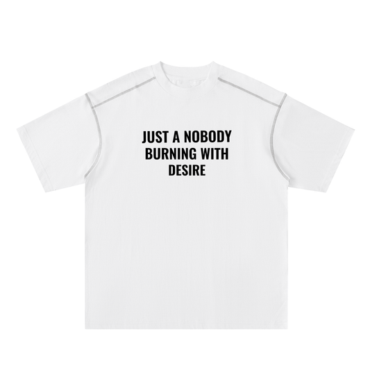 White t-shirt with black text 'JUST A Nobody BURNING WITH DESIRE' on a white background
