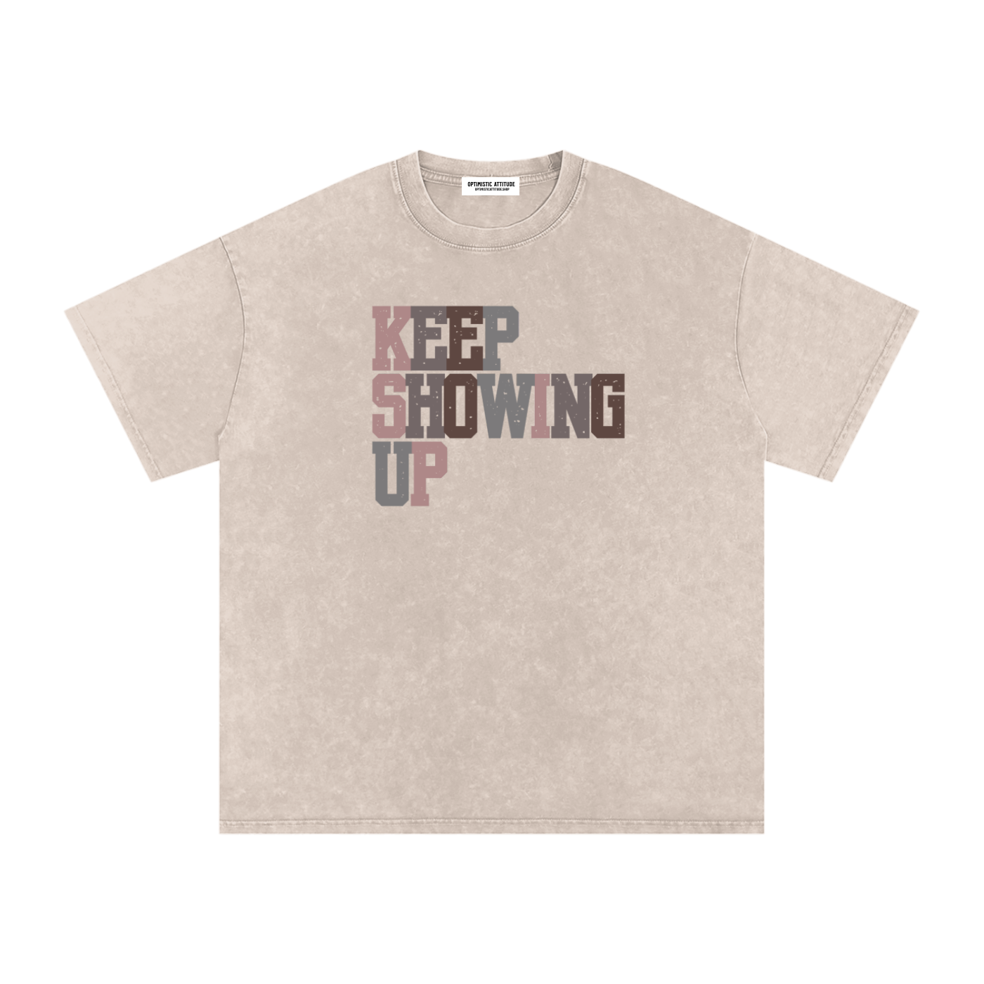 Front of cream t-shirt with "keep showing up" text in the colors light pink, medium gray, mauve, and neutral brown in front of a white background.