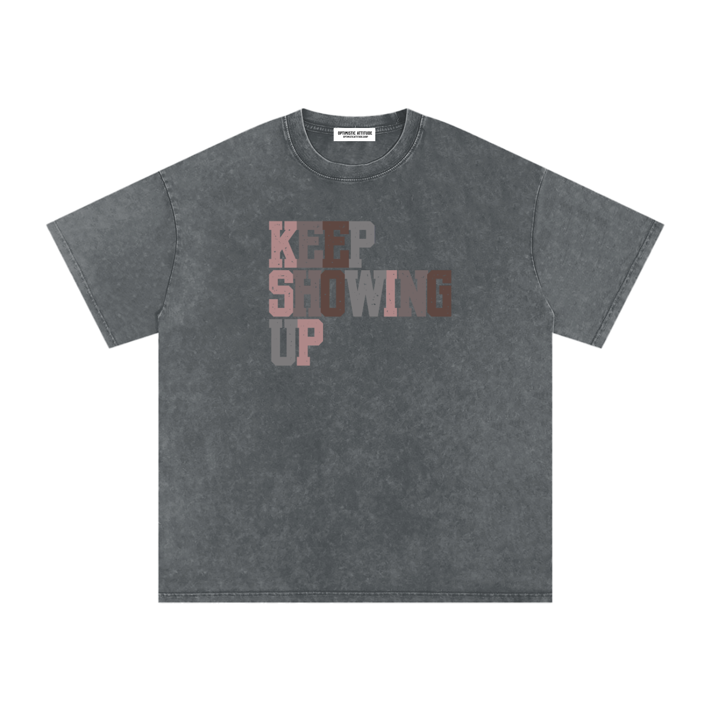 Front of dark gray t-shirt with "keep showing up" text in the colors light pink, medium gray, mauve, and neutral brown in front of a white background.