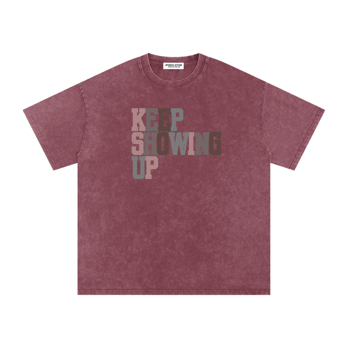 Front of light red t-shirt with "keep showing up" text in the colors light pink, medium gray, mauve, and neutral brown in front of a white background.