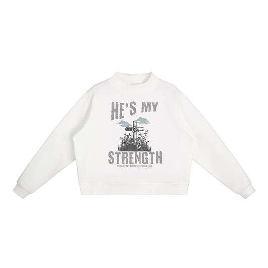 White sweatshirt with graphic design and text on a white background. "He's my strength" text with "I couldn't do it without him" smaller text. Graphic image of cross in a field of grass/flowers with clouds above.