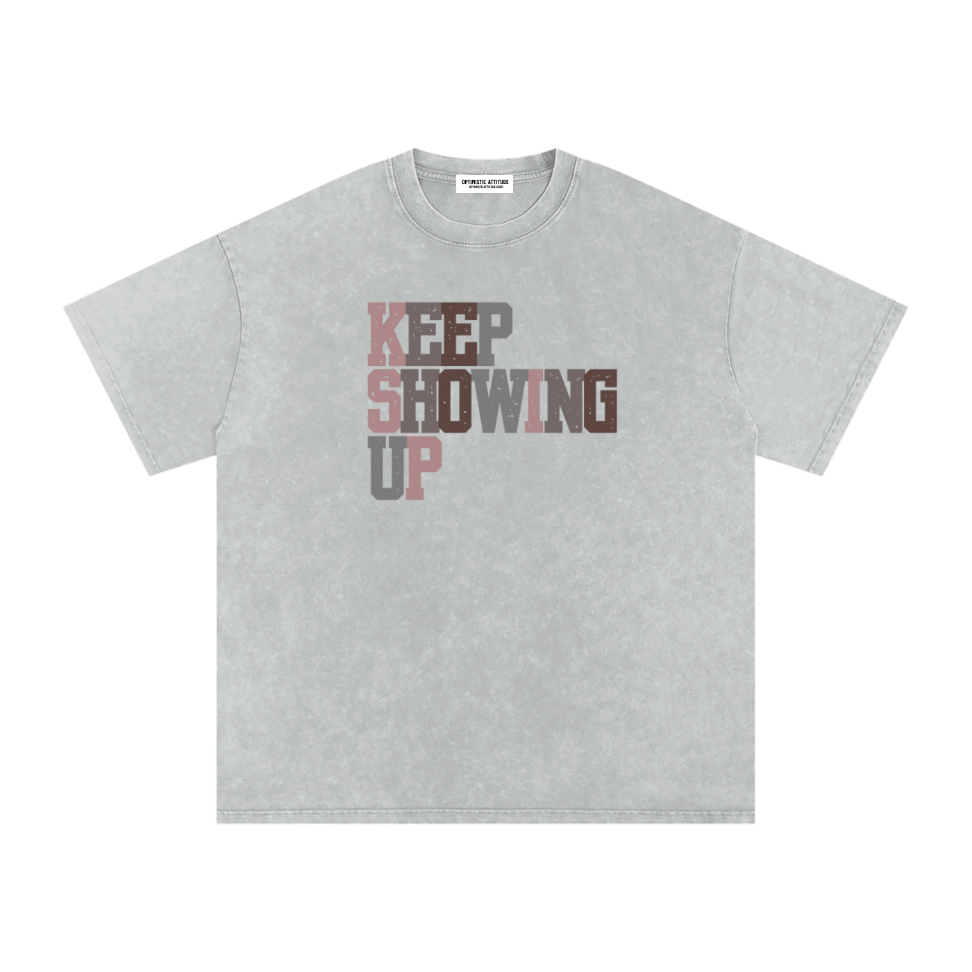 Front of light gray t-shirt with "keep showing up" text in the colors light pink, medium gray, mauve, and neutral brown in front of a white background.