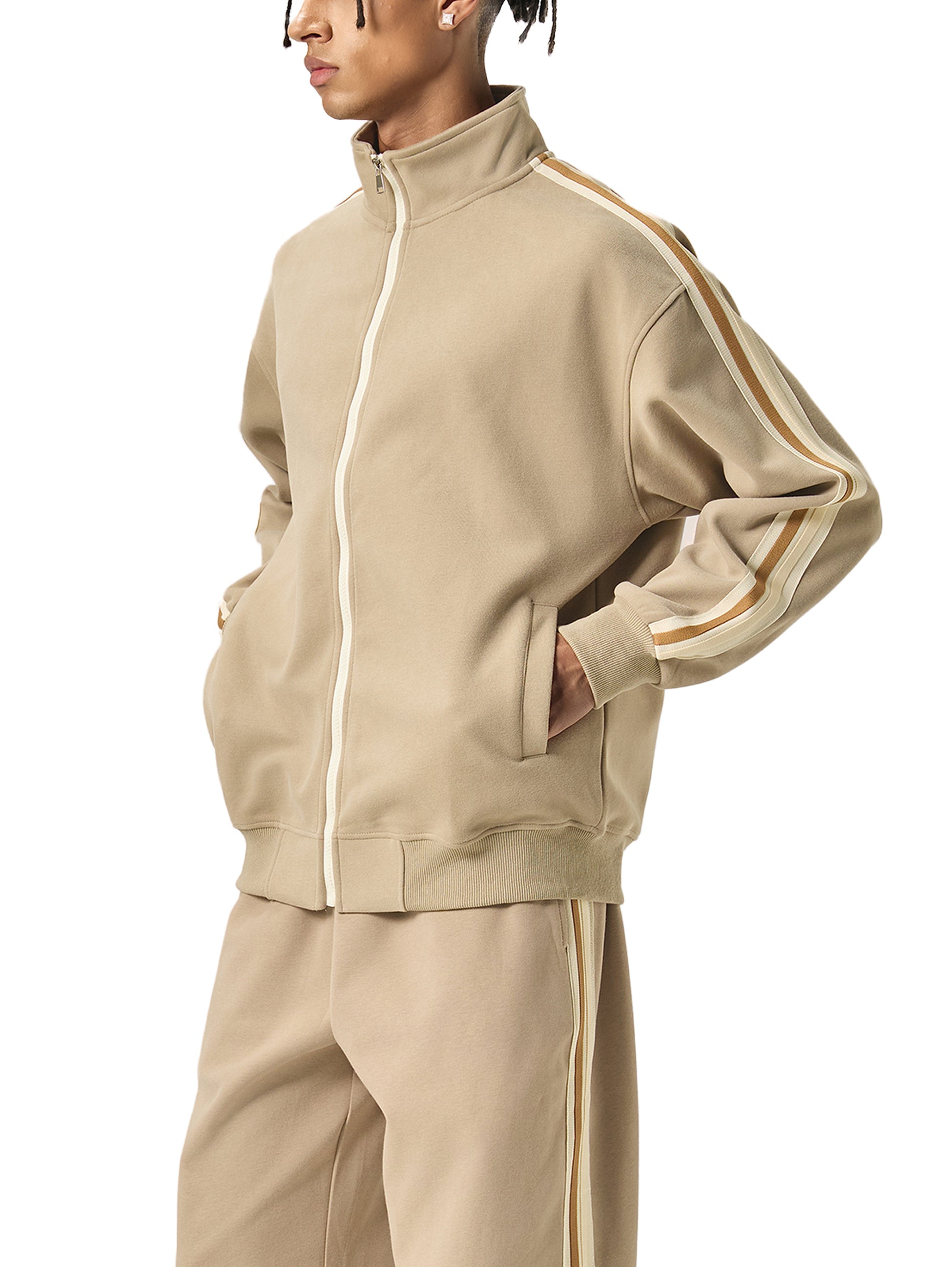 Person wearing a beige tracksuit with white stripes on a white background