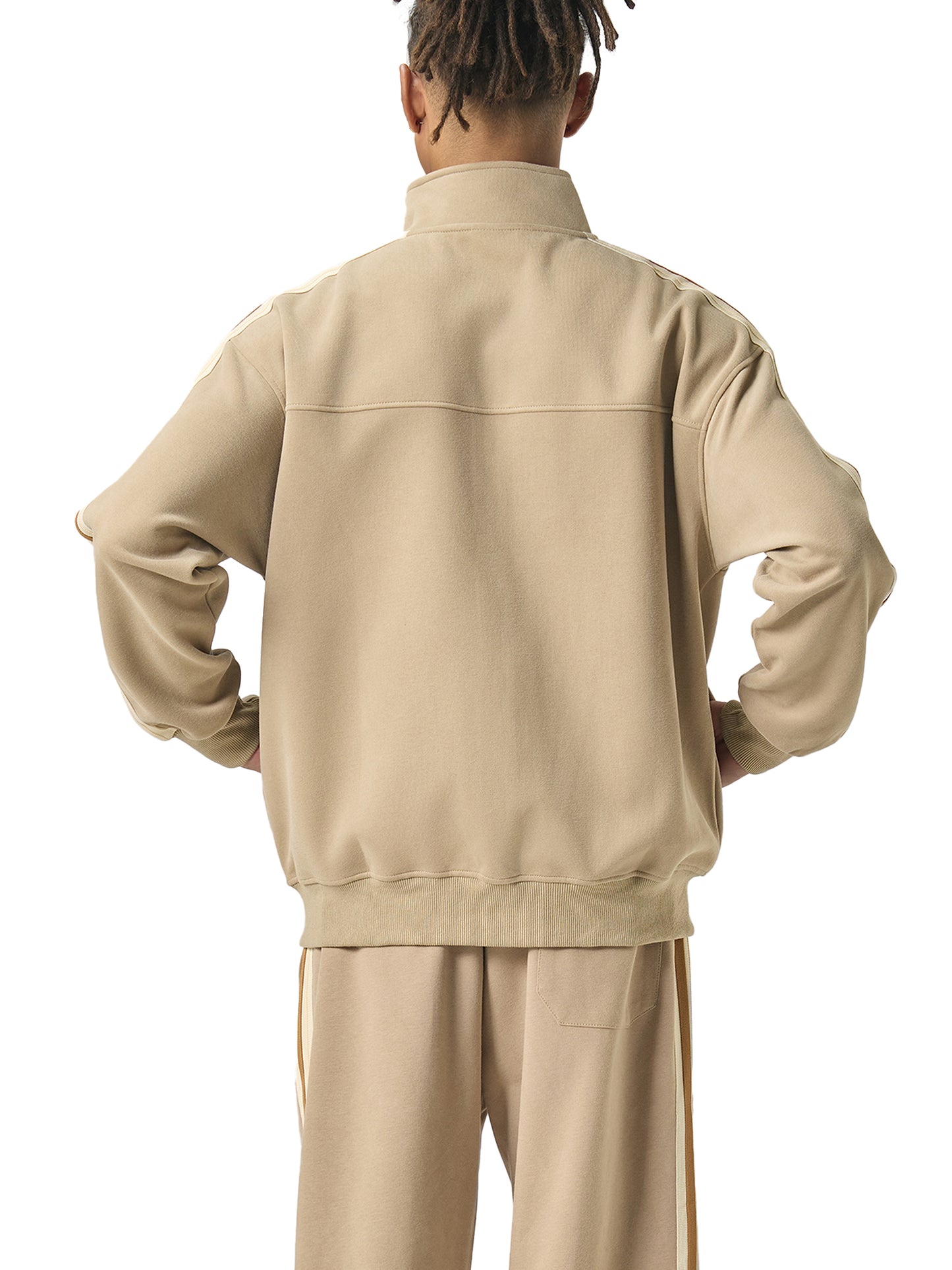 Person wearing a beige tracksuit on a white background
