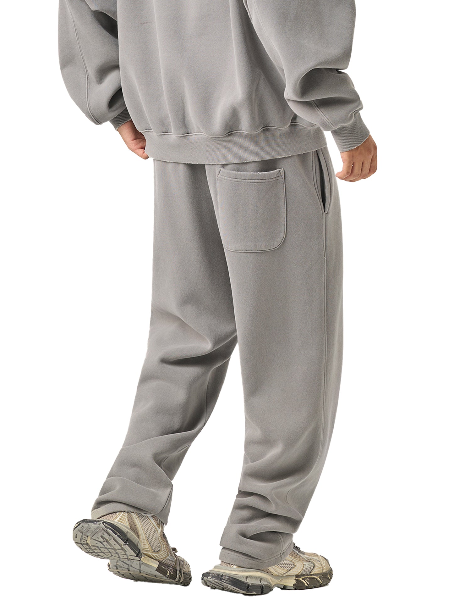 Person wearing a gray tracksuit with a white background