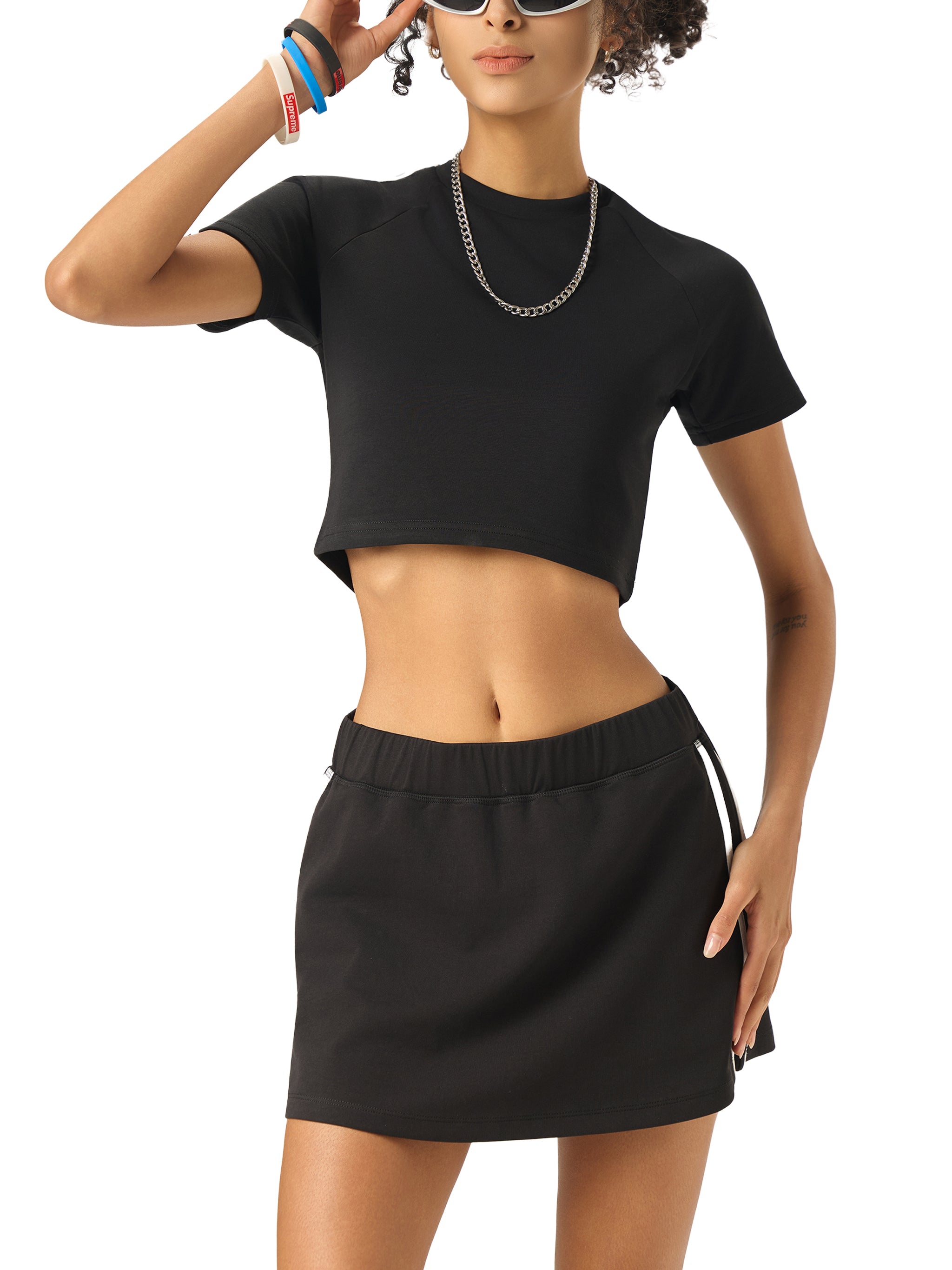 Woman wearing a black crop top and skirt on a white background