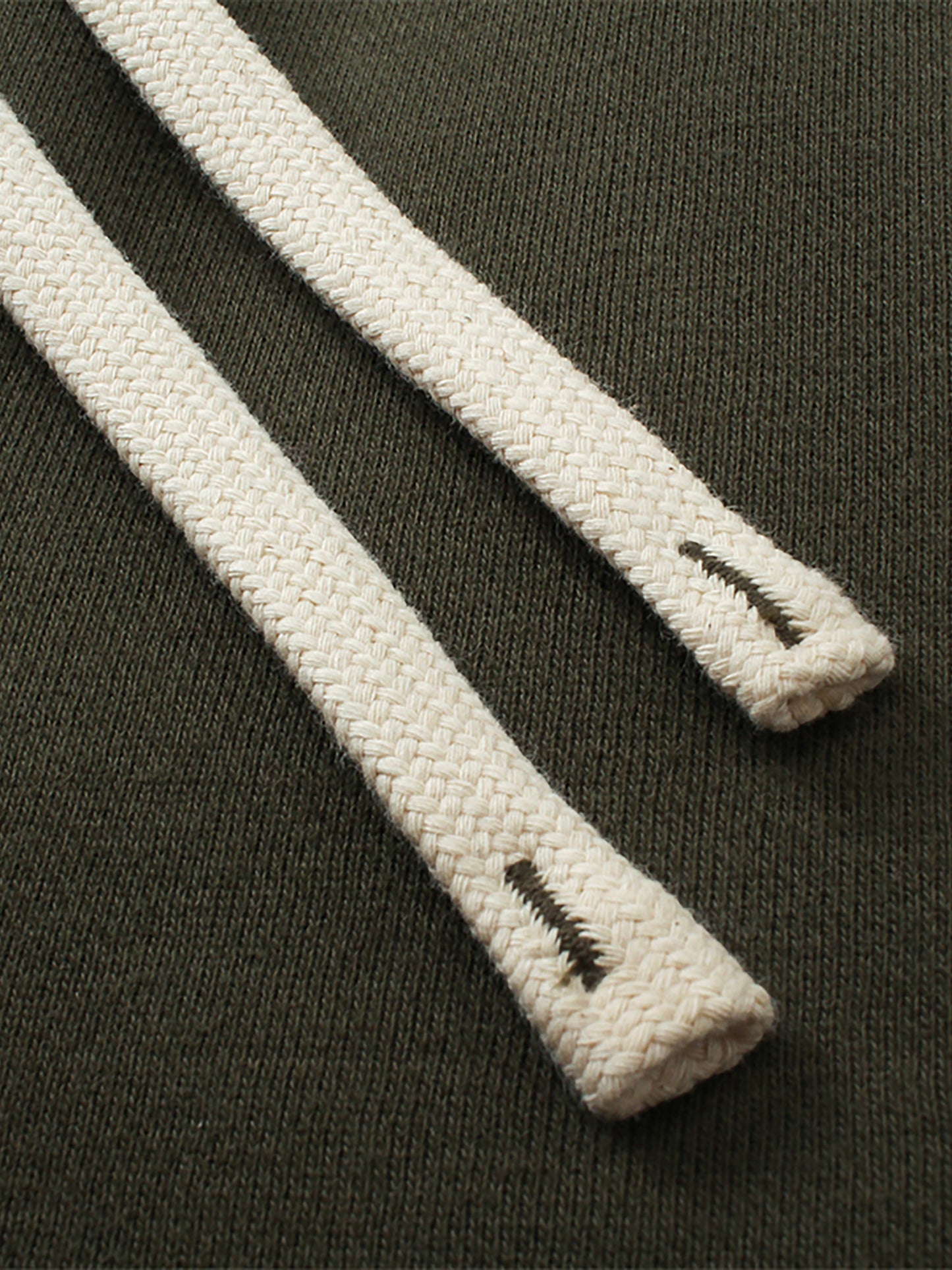 Close-up of white drawstring on dark green sweatpants